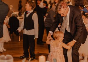 Cute image of bride's daughter dancing with her grandfather during the reception, capturing a joyful family moment.