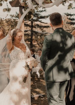 Timeless candid moment of bride adjusting her veil at the altar, capturing a beautiful wedding detail.