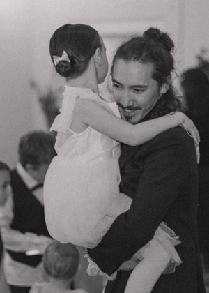 Brother-in-law of the bride holding a child in a sweet moment, captured in black and white for a timeless look.
