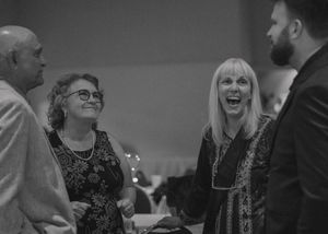 Candid moment of the groom with guests during the reception, captured in black and white.