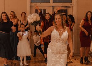 Bride about to throw her bouquet, surrounded by excited guests, in vibrant color.