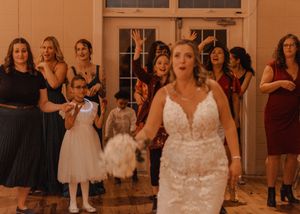 Candid moment of guests reaching for the bouquet as Bride is about to toss.