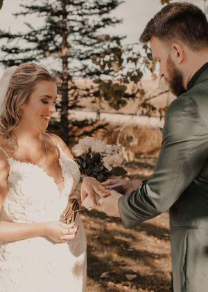 Groom placing the wedding ring on the bride's finger during the ceremony, capturing a tender moment.