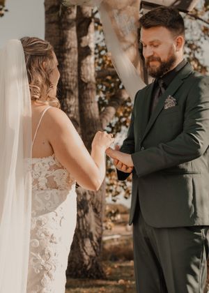 Bride placing the wedding ring on the groom's finger during the ceremony, capturing the moment.