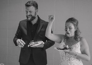 Funny moment of bride and groom post-cake smash, with the bride joyfully celebrating.