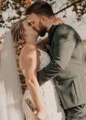 Bride and groom share their first kiss, beautifully captured in vibrant color.
