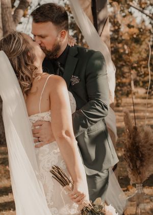 Bride and groom share their first kiss, beautifully captured in vibrant color.
