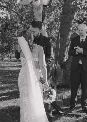 Bride and groom sharing their first kiss, captured in timeless black and white.