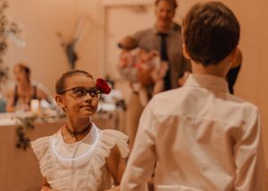 Cute photo of kids at reception, girl looking at boy with a flower tucked behind her ear.