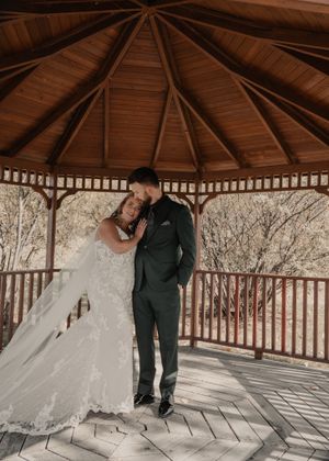 After the first look, bride and groom pose together in a gazebo surrounded by fall foliage.