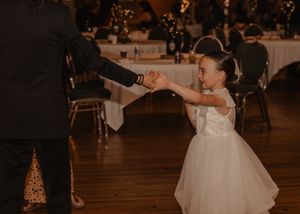 Candid moment of a girl encouraging a wedding guest to join her on the dance floor.