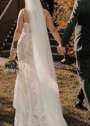 Bride and groom walking hand in hand through a picturesque fall scene, showcasing the bride's white rose bouquet.