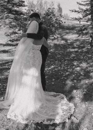 Candid black and white photo of a bride and groom sharing a first moment after the wedding, groom's arm around bride.