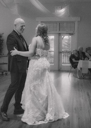 Black and white photo of bride and father sharing a heartfelt dance, capturing an emotional and timeless moment.