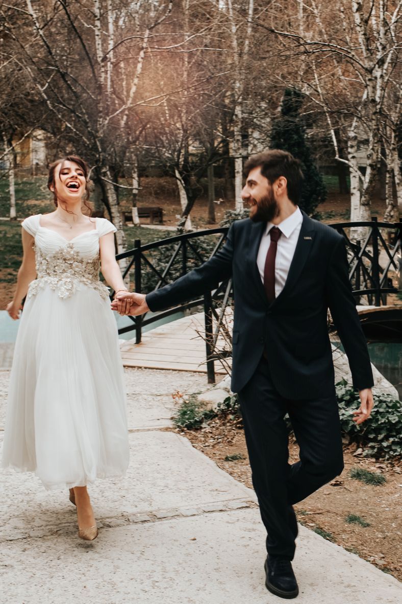 A romantic moment on a bridge with autumn trees in the background during a wedding.