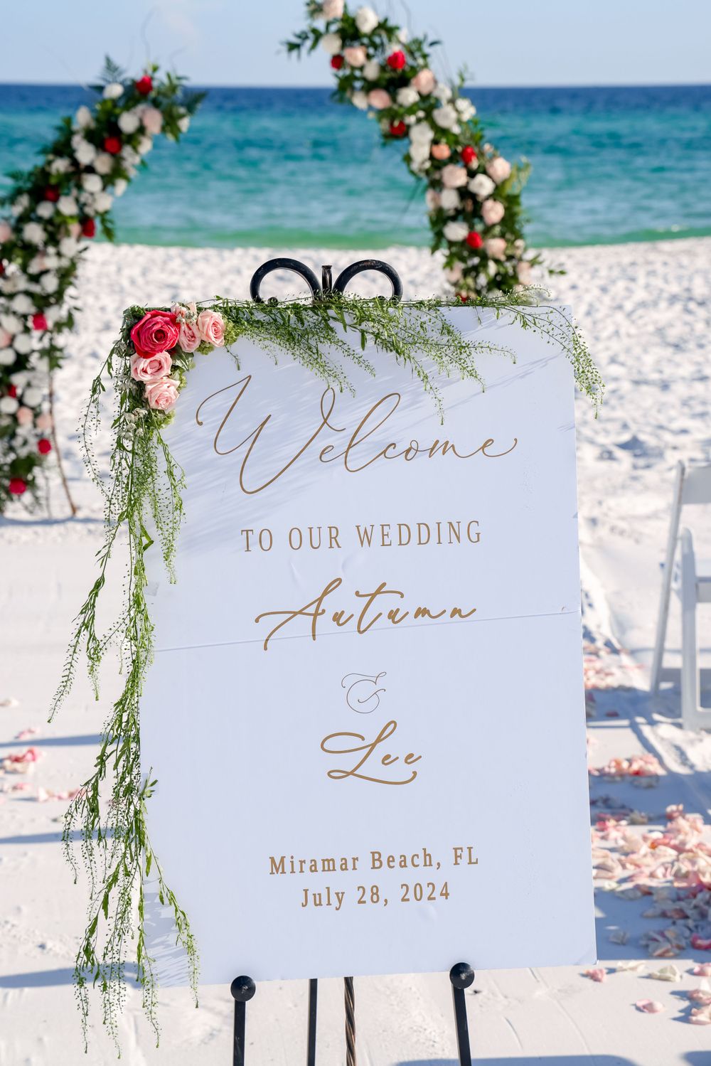 Beach wedding welcome sign with floral arch decoration at Miramar Beach, Florida.
