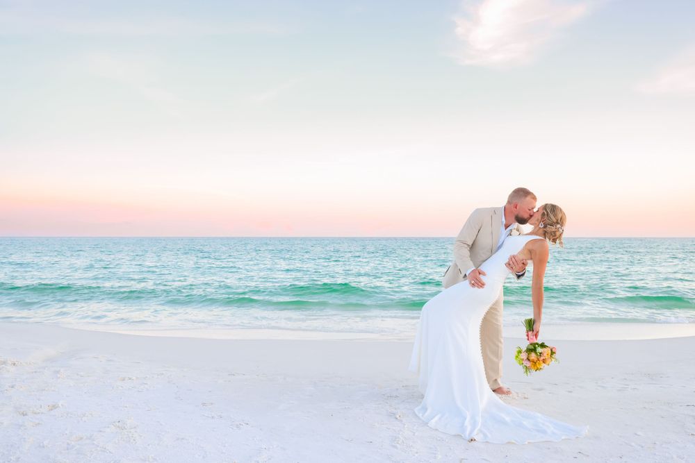 Romantic beach wedding portrait during sunset with turquoise ocean backdrop.