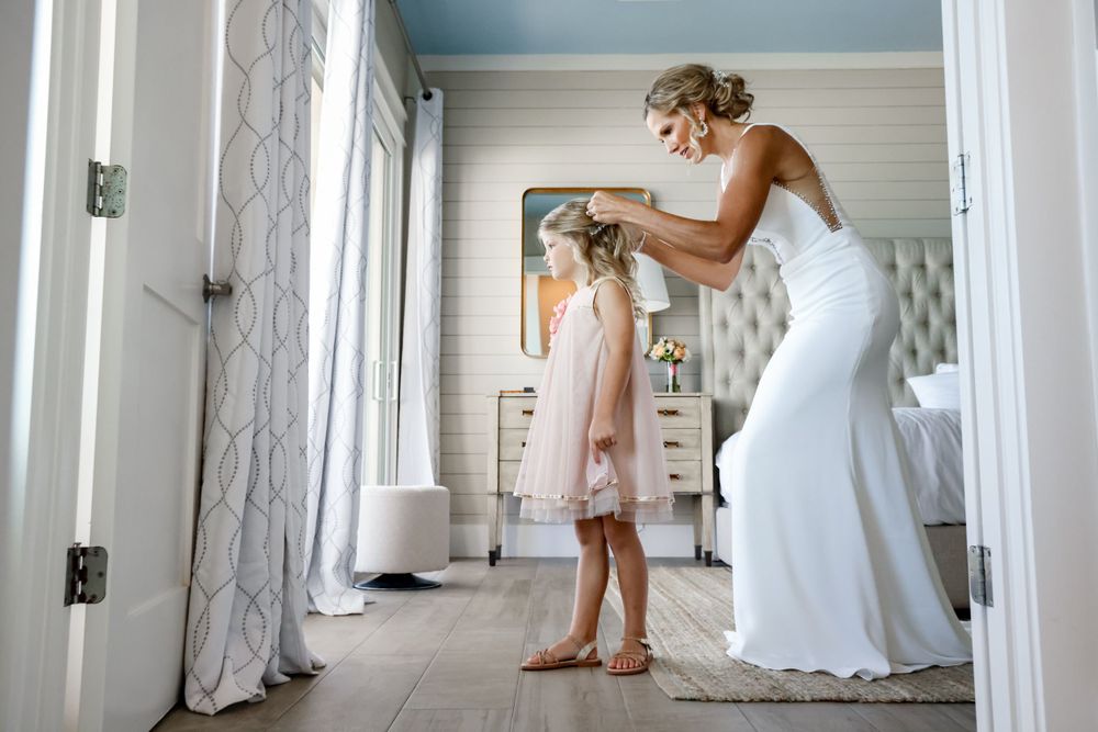 A tender moment shared while getting ready in a sunlit room with elegant white decor.