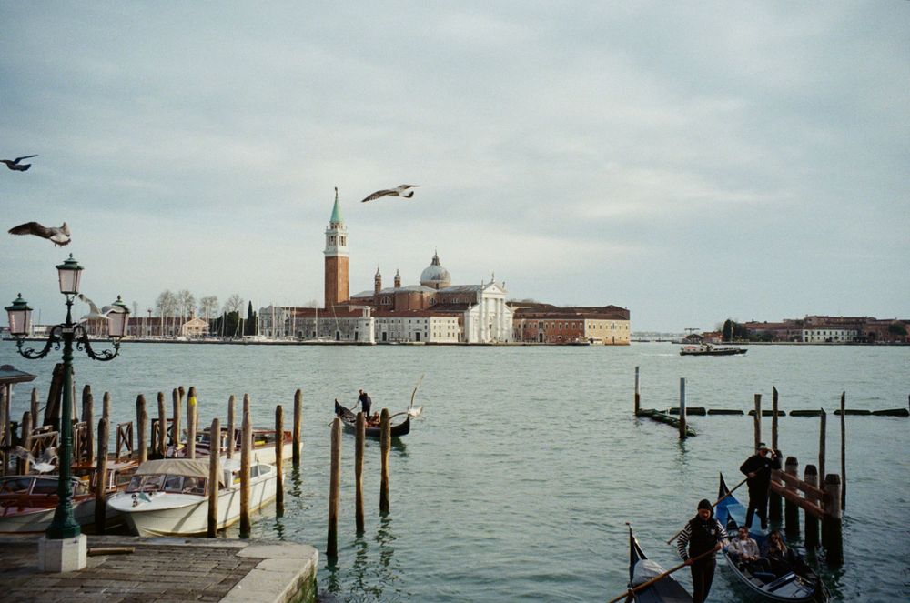 View of San Giorgio Maggiore church across the Venice lagoon with boats and docking posts.