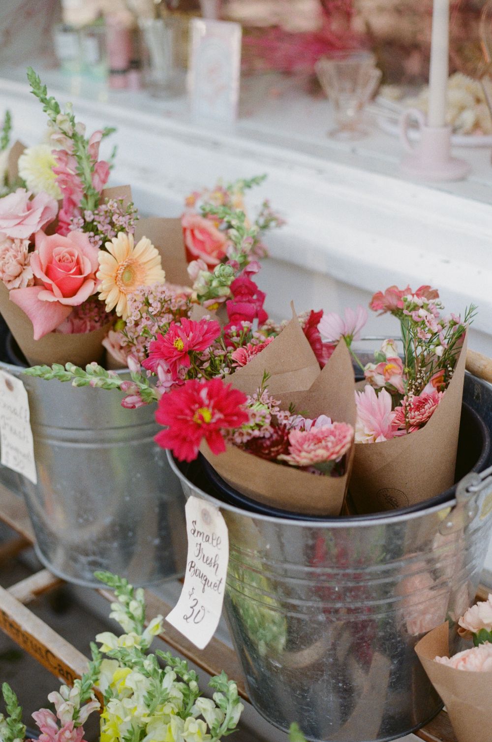 Fresh flower bouquets in metal buckets featuring pink roses and gerbera daisies.