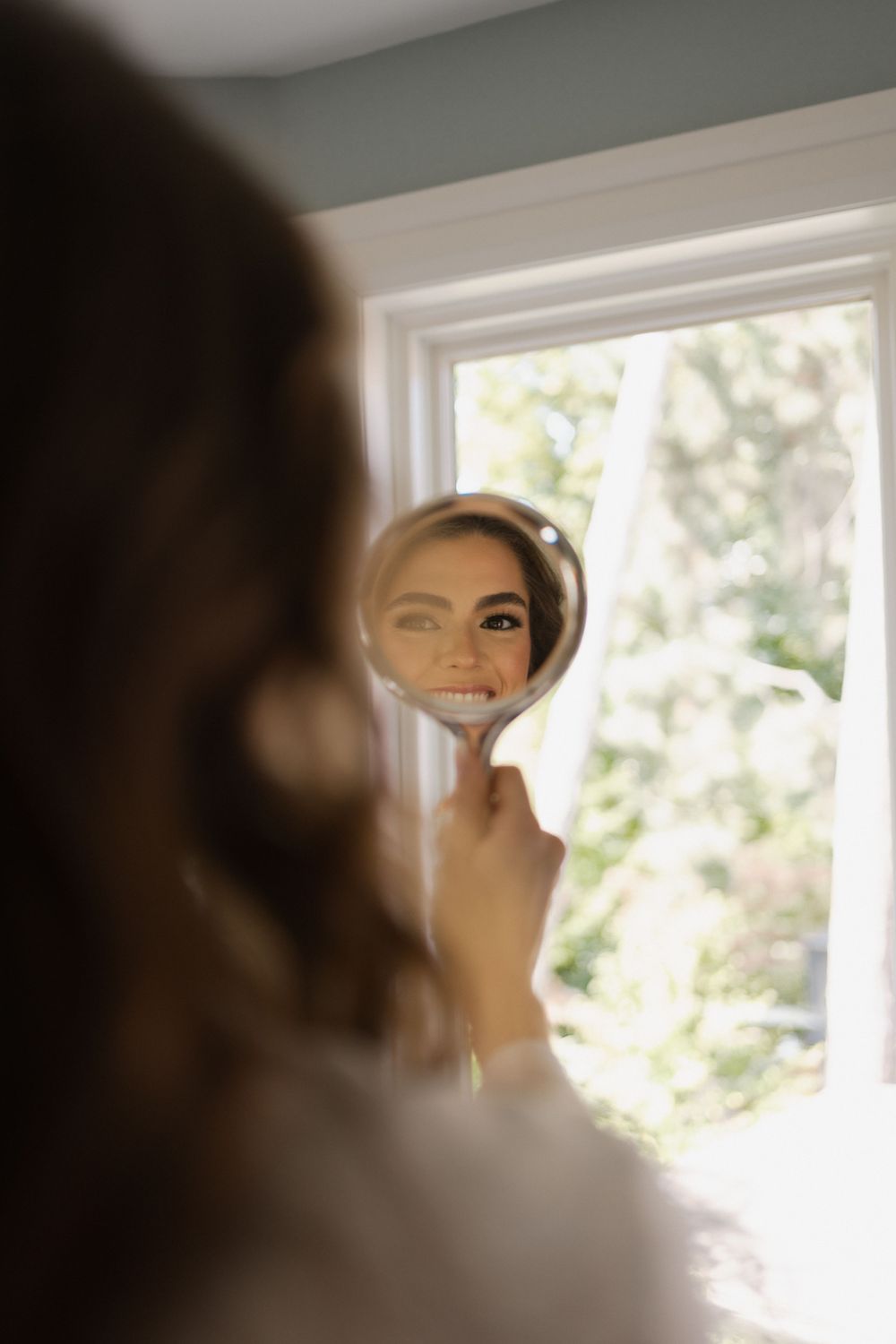 Close up reflection of smile in round mirror with window light.