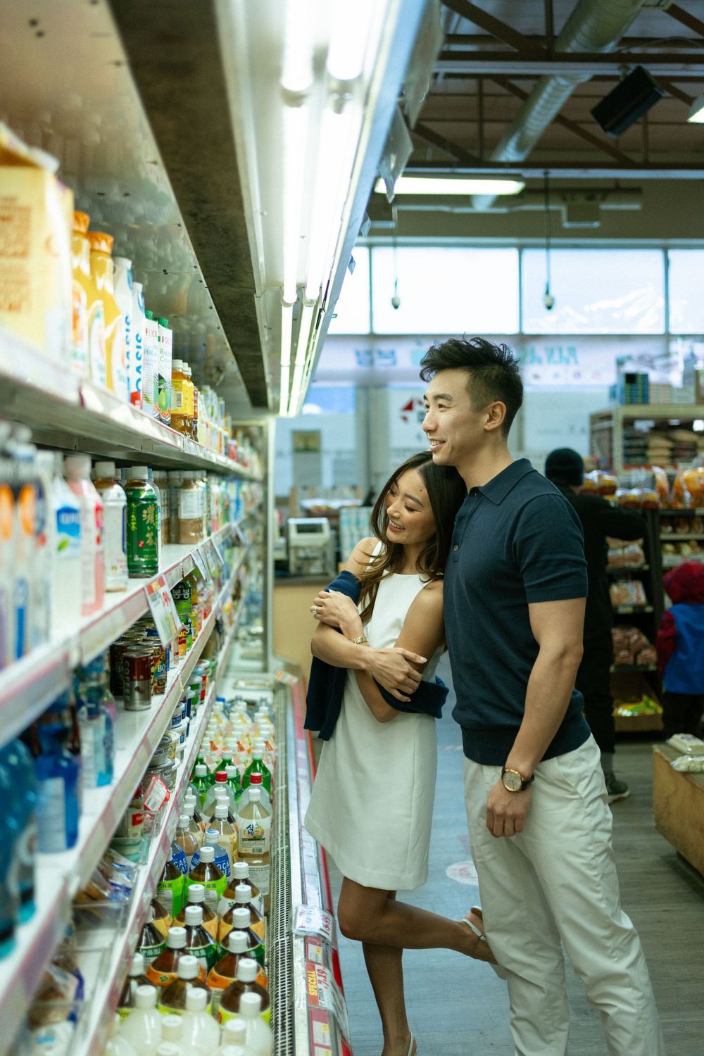 Couple shopping together in grocery store aisle looking at products on shelves.