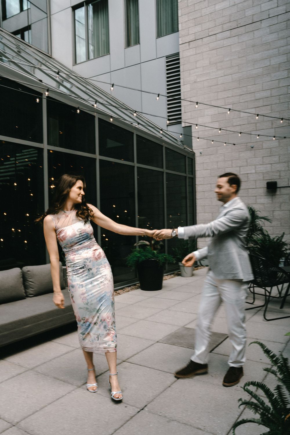 Couple dancing together on modern urban patio with string lights.