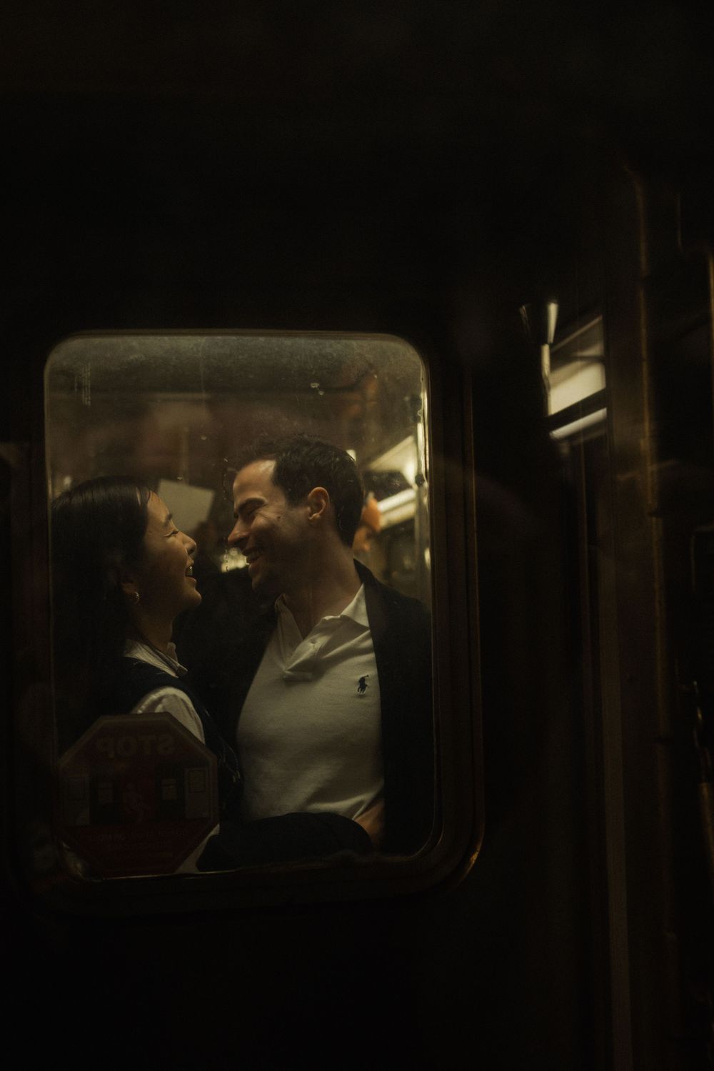 A couple sharing an intimate moment viewed through a train window at night.