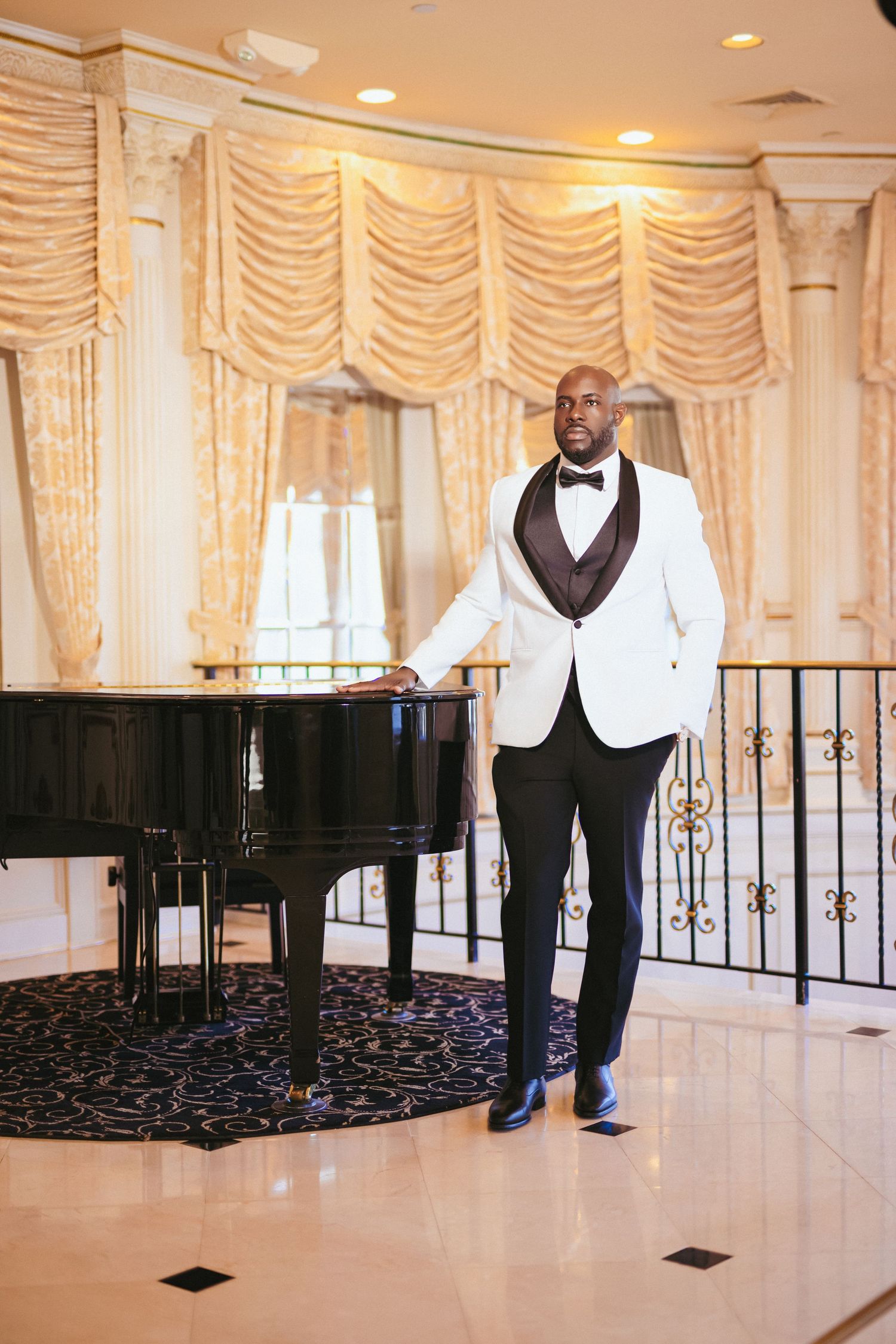 Formal event setting with white tuxedo jacket and grand piano against elegant draped curtains in an ornate ballroom.