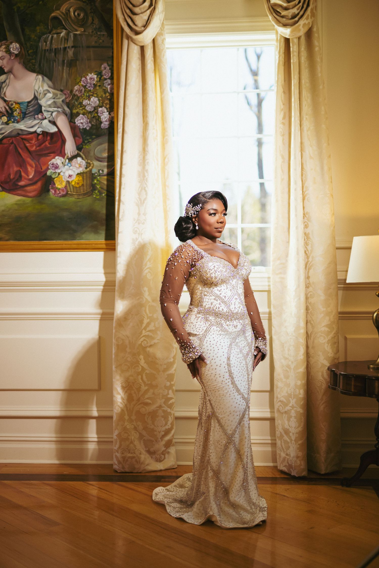 A stunning bridal portrait in a formal room with elegant drapes and classical artwork, wearing a beaded wedding gown.