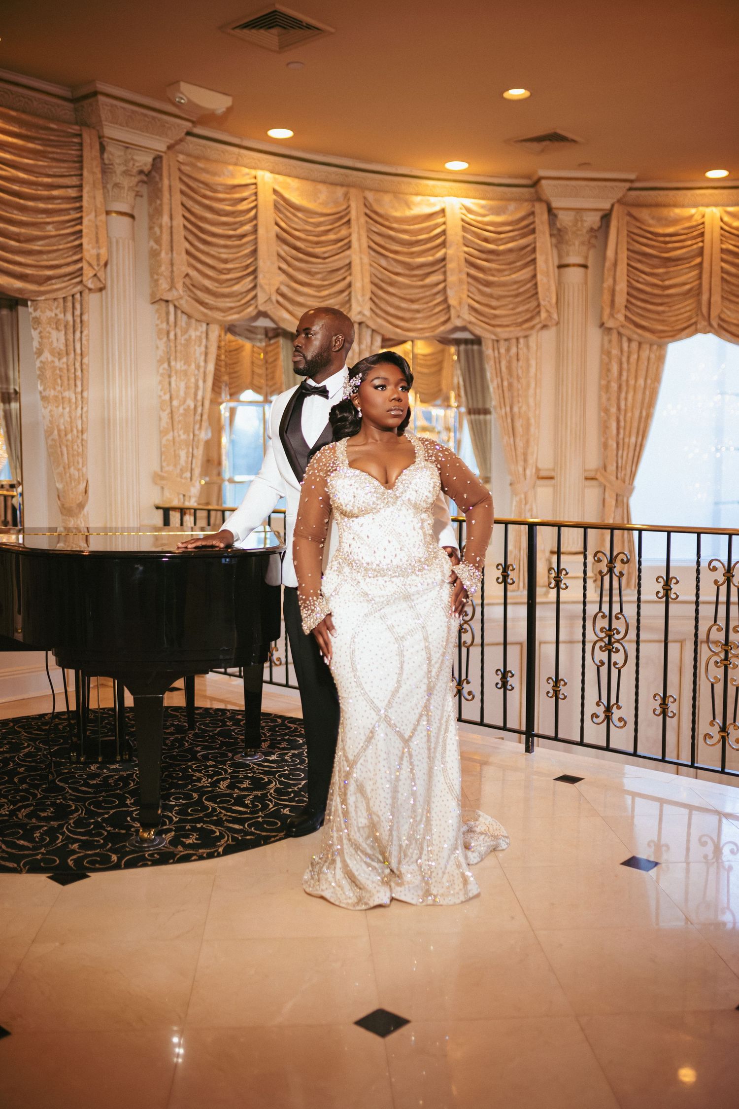 An elegant bridal photo in a grand ballroom with a piano and draped windows, showcasing a sequined gown.