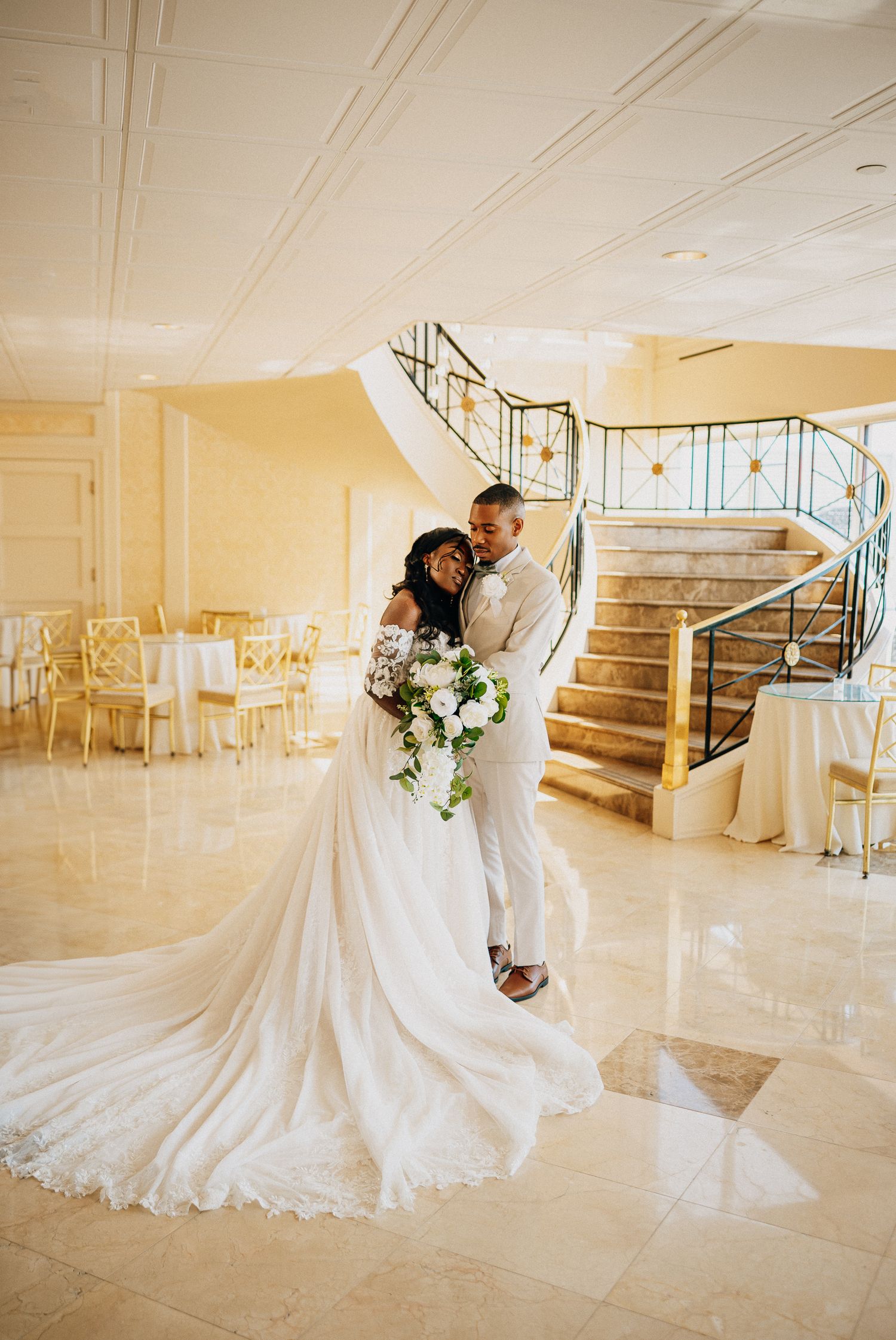 A couple shares a romantic dance in a grand ballroom with elegant marble floors and ornate staircase.
