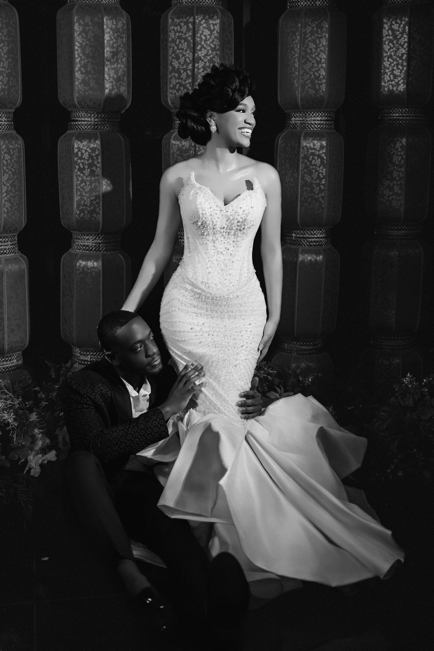 Black and white wedding photo showing couple posing together, with bride wearing elegant fitted mermaid gown.