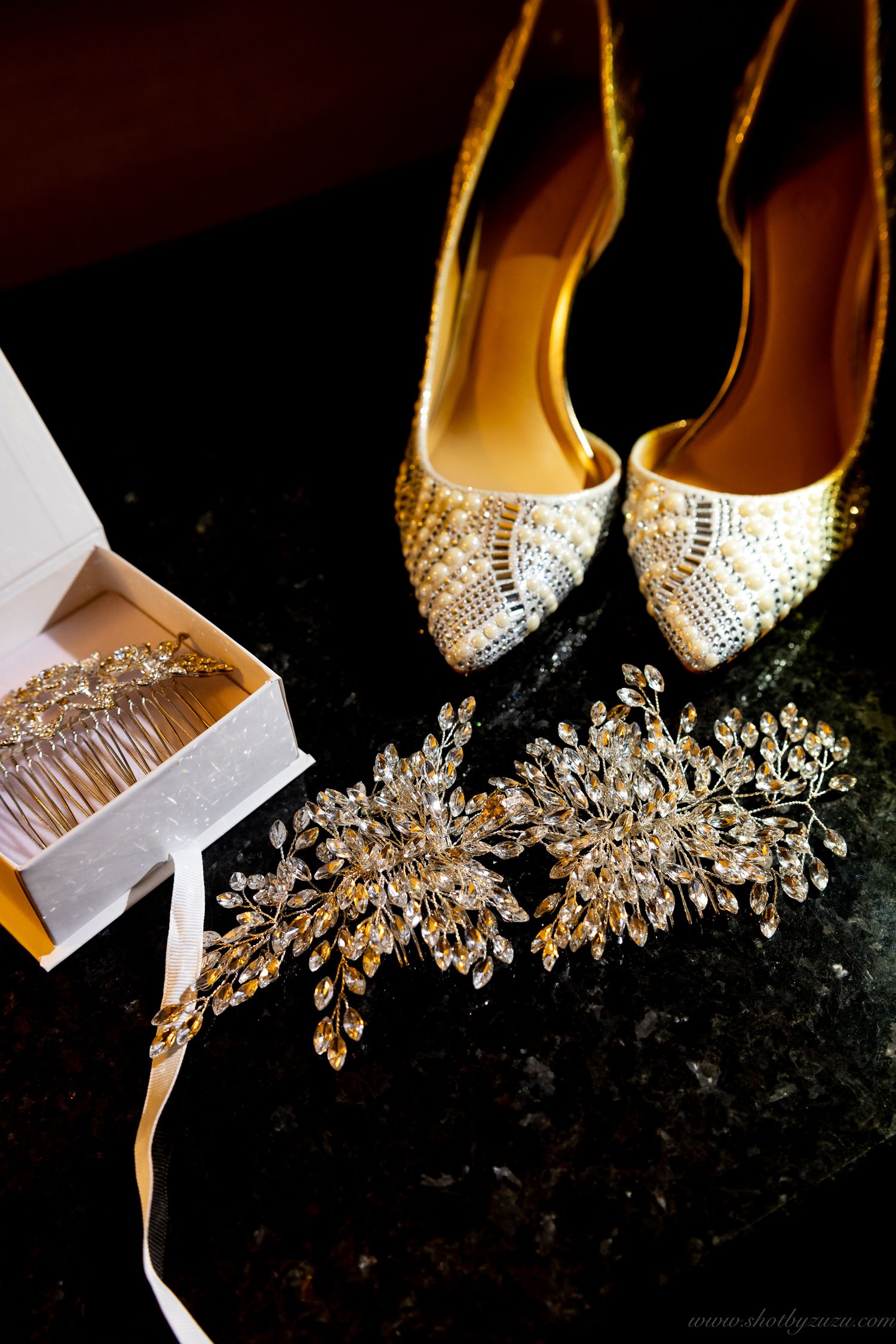 Sparkly bridal accessories including crystal shoes and hair pieces arranged on dark surface.