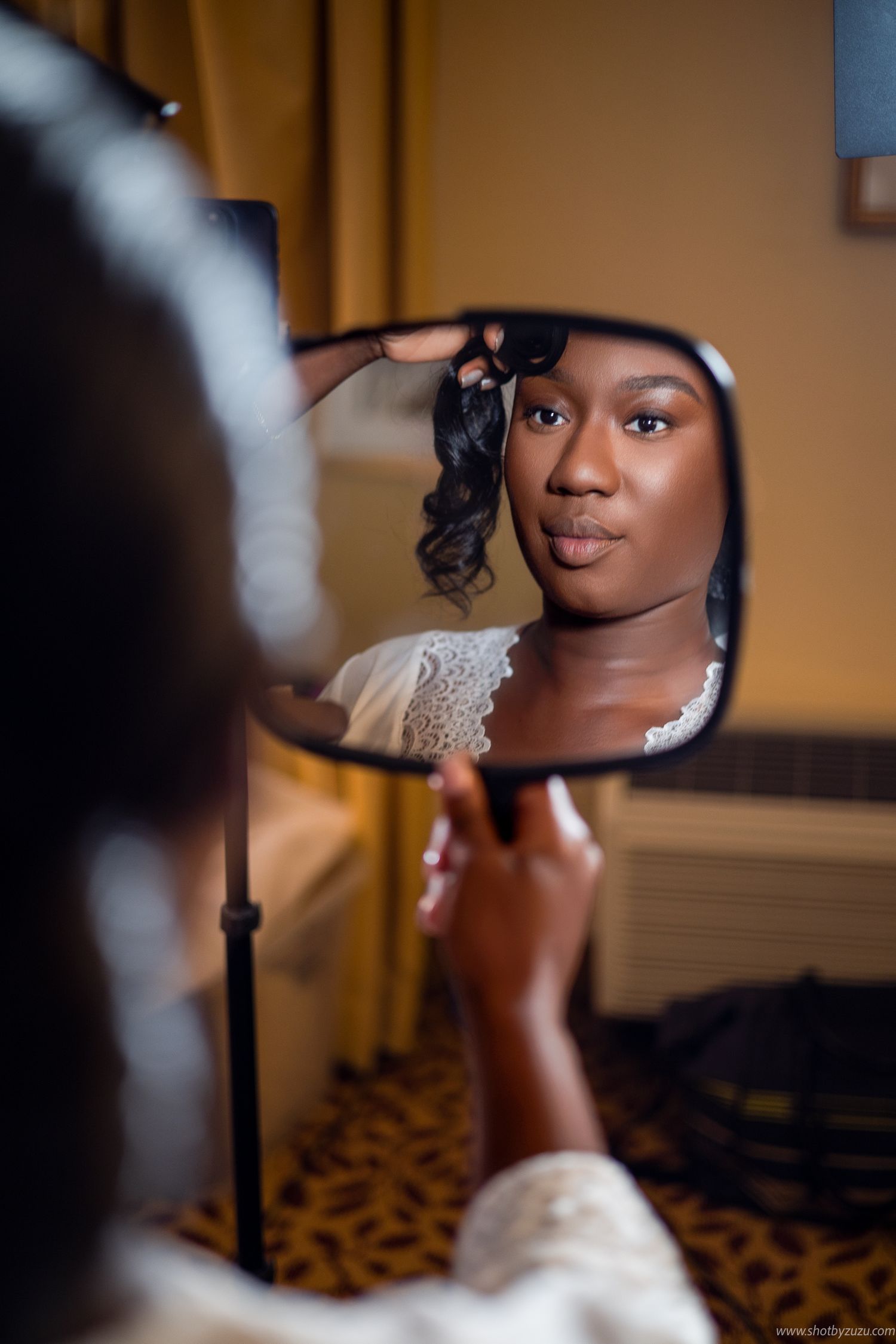 A reflection shows bridal makeup preparation in a handheld mirror.