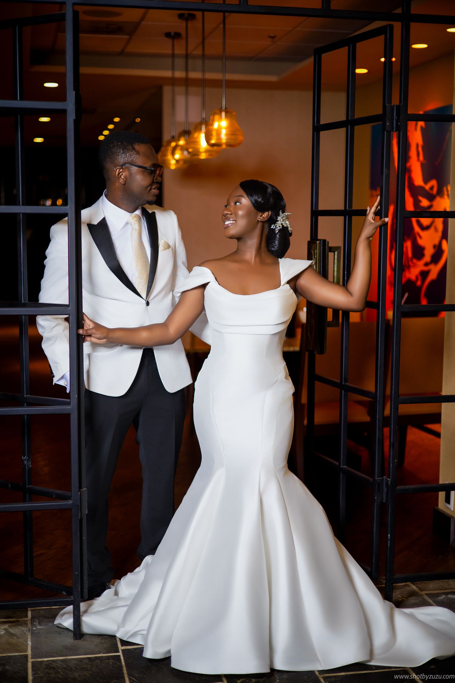 A stylish wedding couple poses in a modern venue with dramatic lighting and industrial decor.