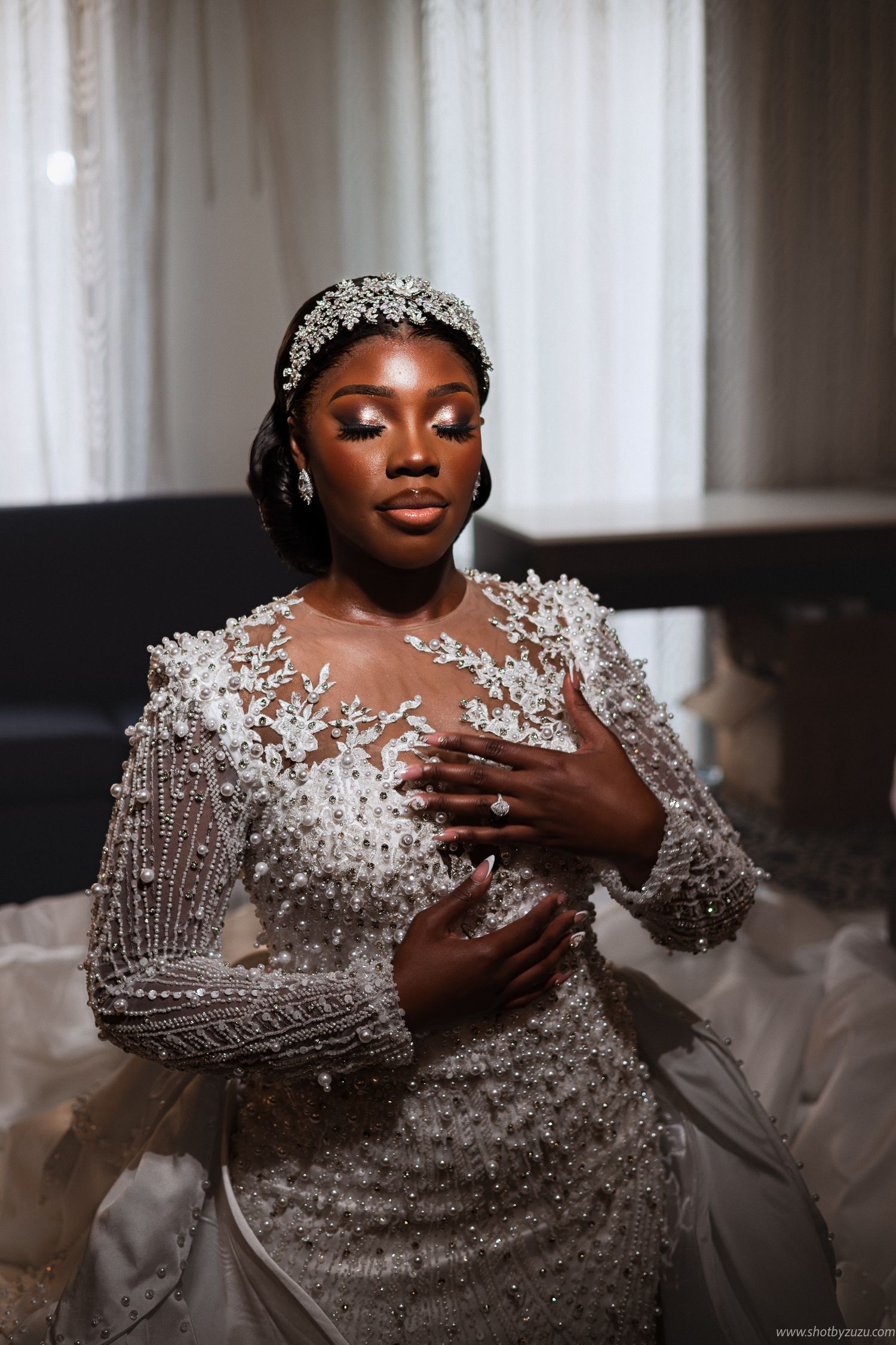 A bride wears an intricately beaded long-sleeve wedding gown with a crystal headpiece.
