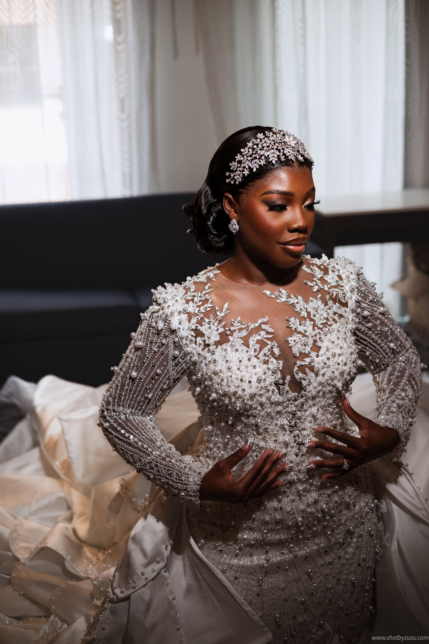 A stunning bridal portrait features a beaded long-sleeve gown and crystal hair accessories.