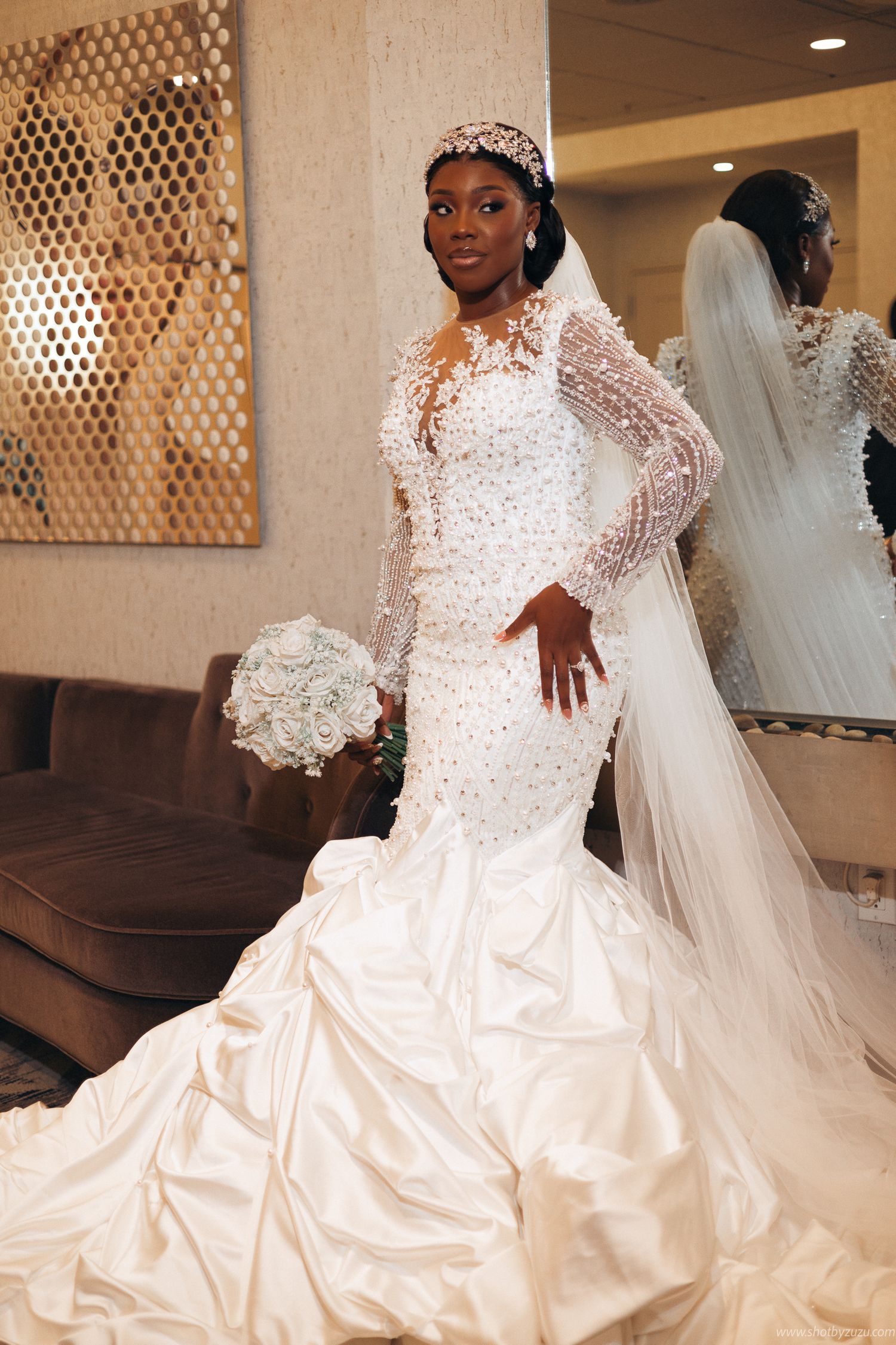 A mermaid-style wedding gown with beaded details and long sleeves sparkles in natural light.