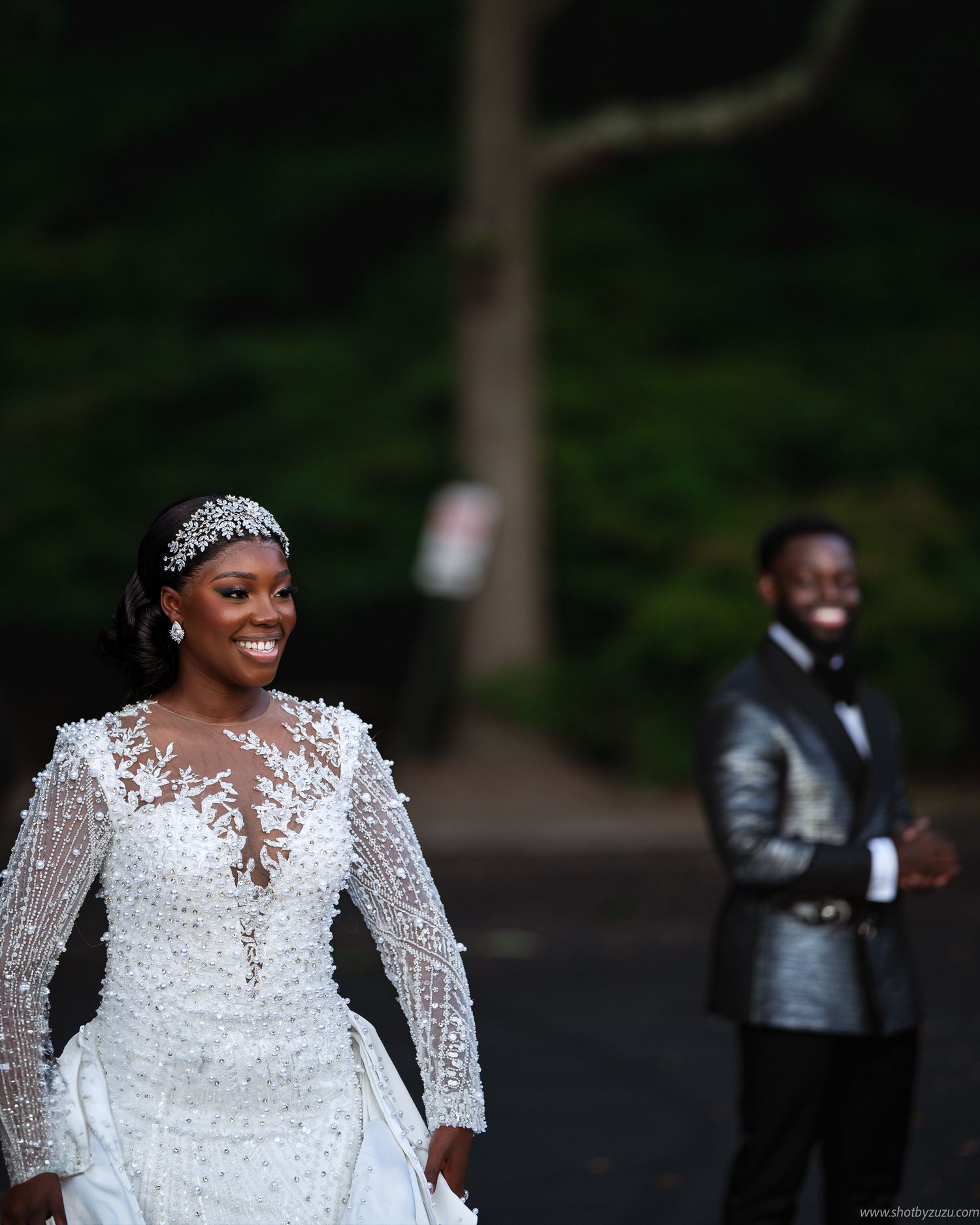 Romantic wedding photo showing couple in white lace gown and metallic gray suit outdoors.