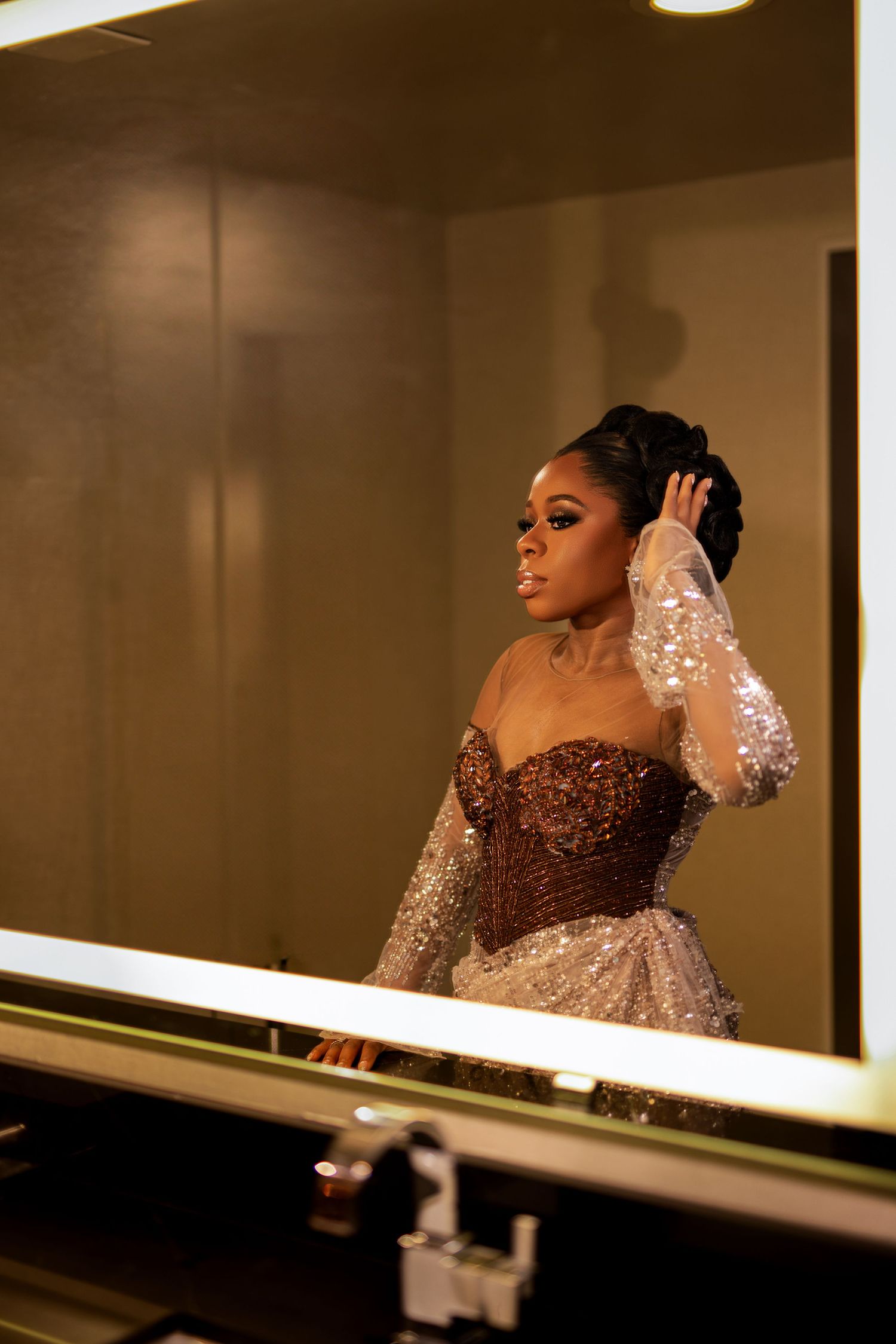 Elegant evening gown with brown sequined bodice and sheer sleeves captured in a mirror reflection.
