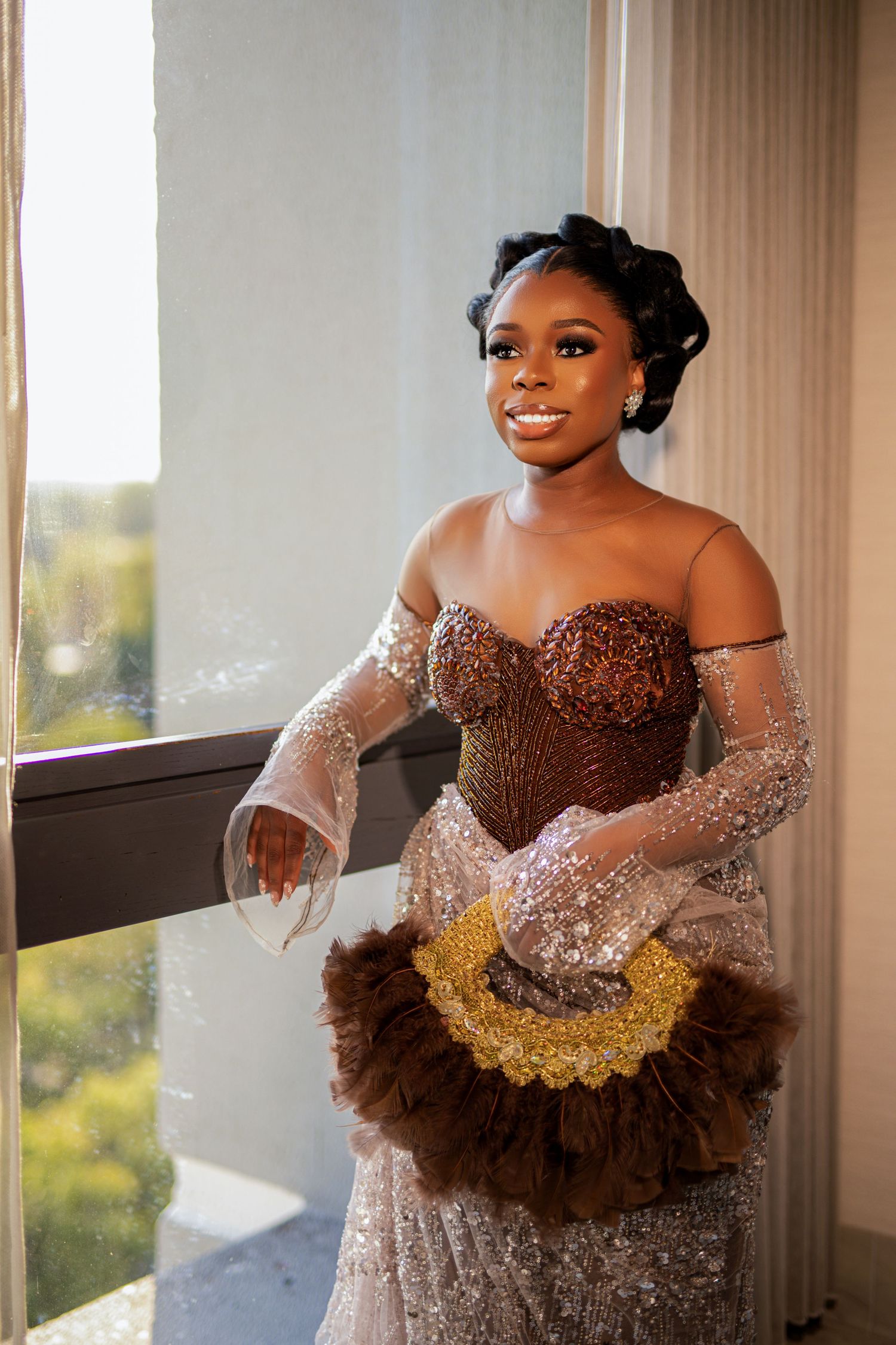 Glamorous shot of person in sequined brown gown with lace sleeves holding decorative fan.