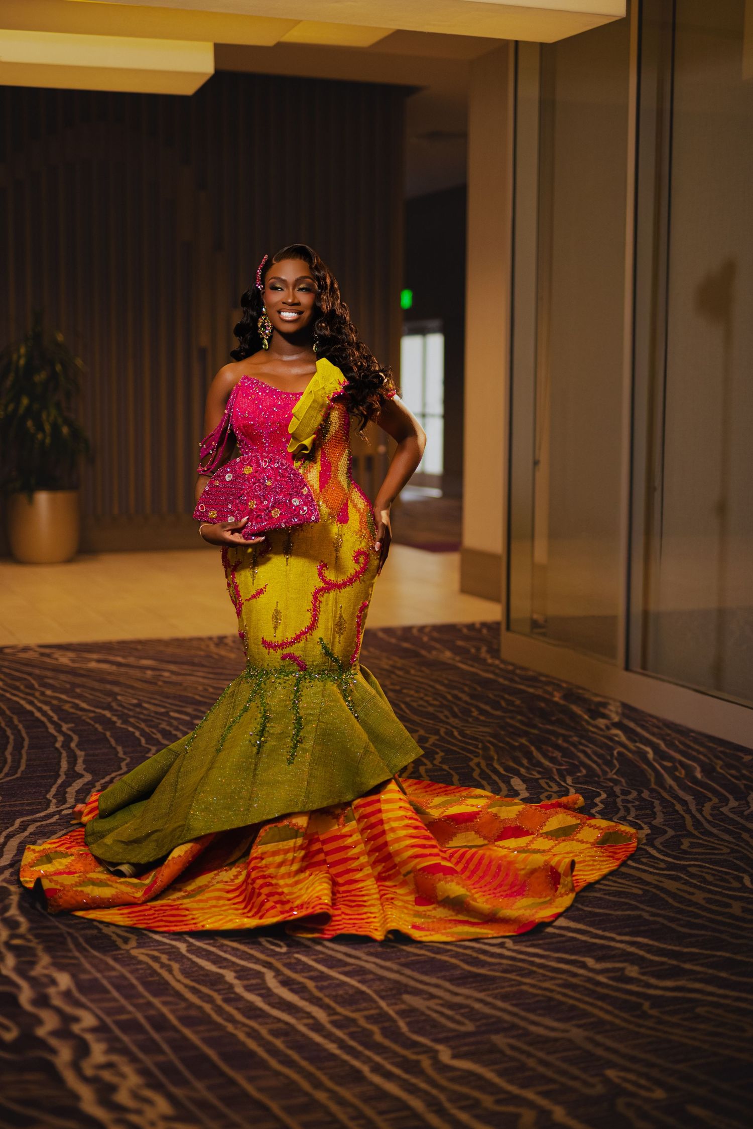 A formal evening gown in vibrant yellow and red with a dramatic mermaid silhouette and ruffled details.