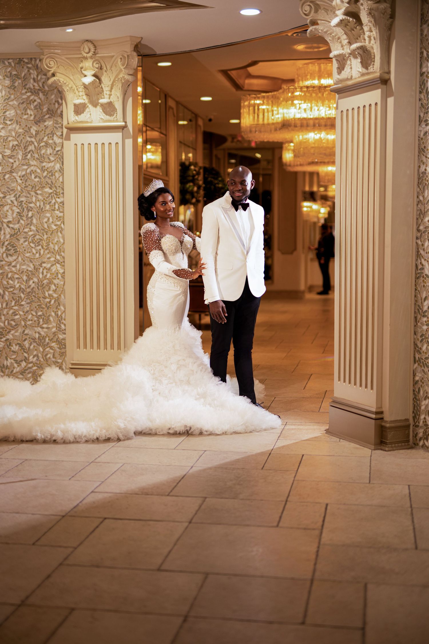 Stunning white wedding gown with dramatic train photographed in elegant hotel corridor.