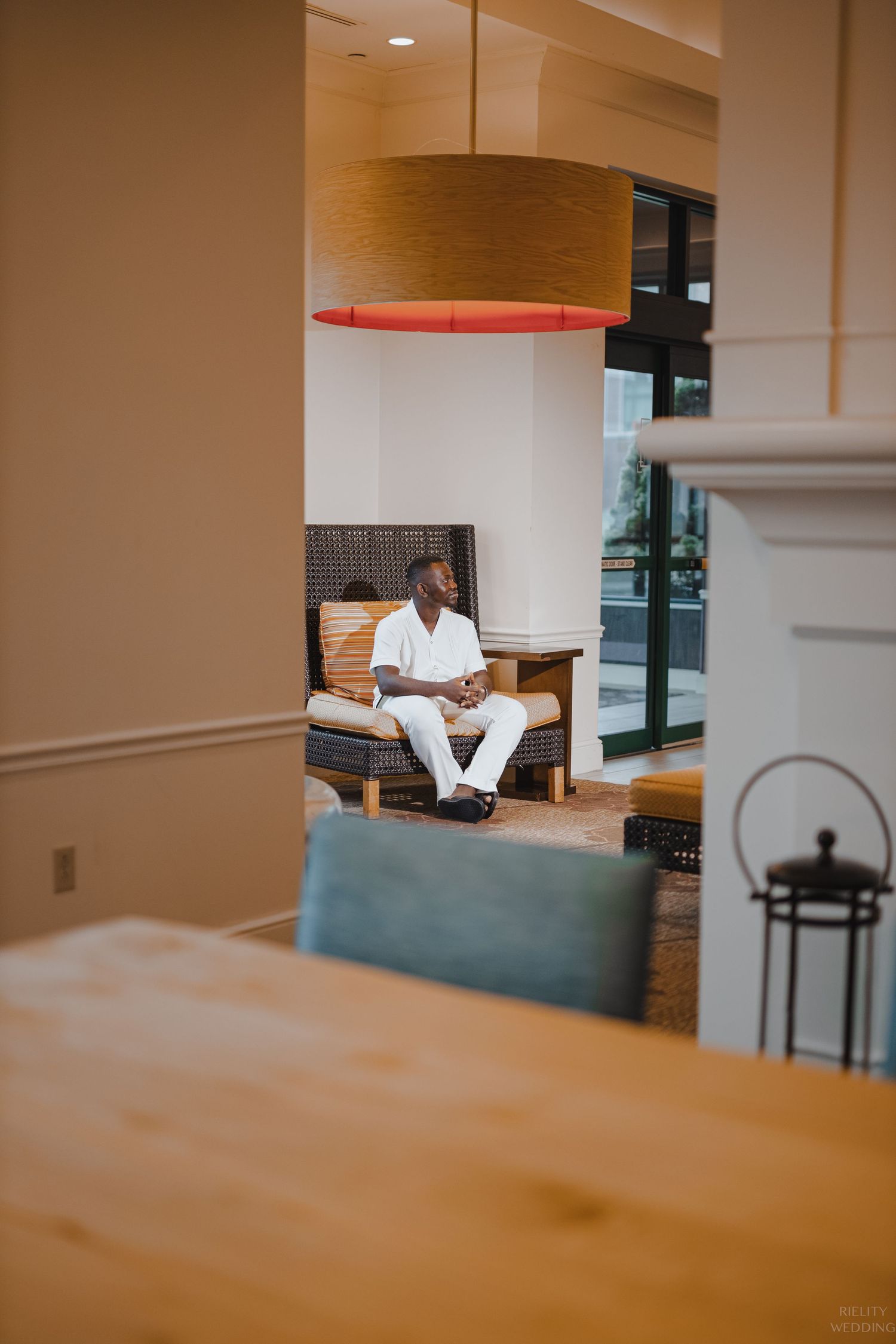 Interior view of person relaxing on bench through doorway under modern lighting fixture.
