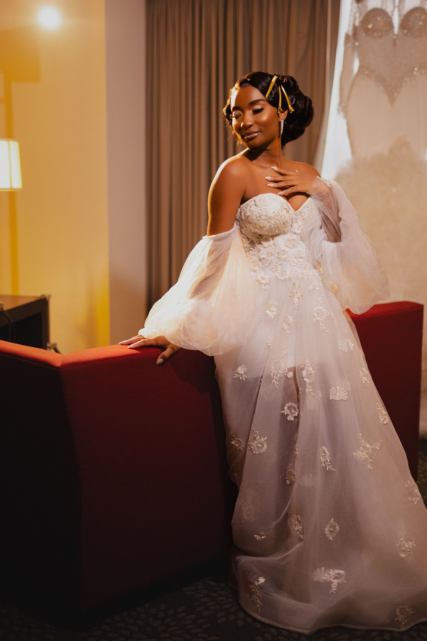 Stunning wedding gown with lace details and off-shoulder design in warm-lit room.