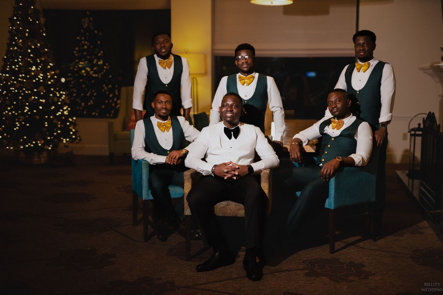 Group photo of wedding party members in coordinated attire by Christmas tree.