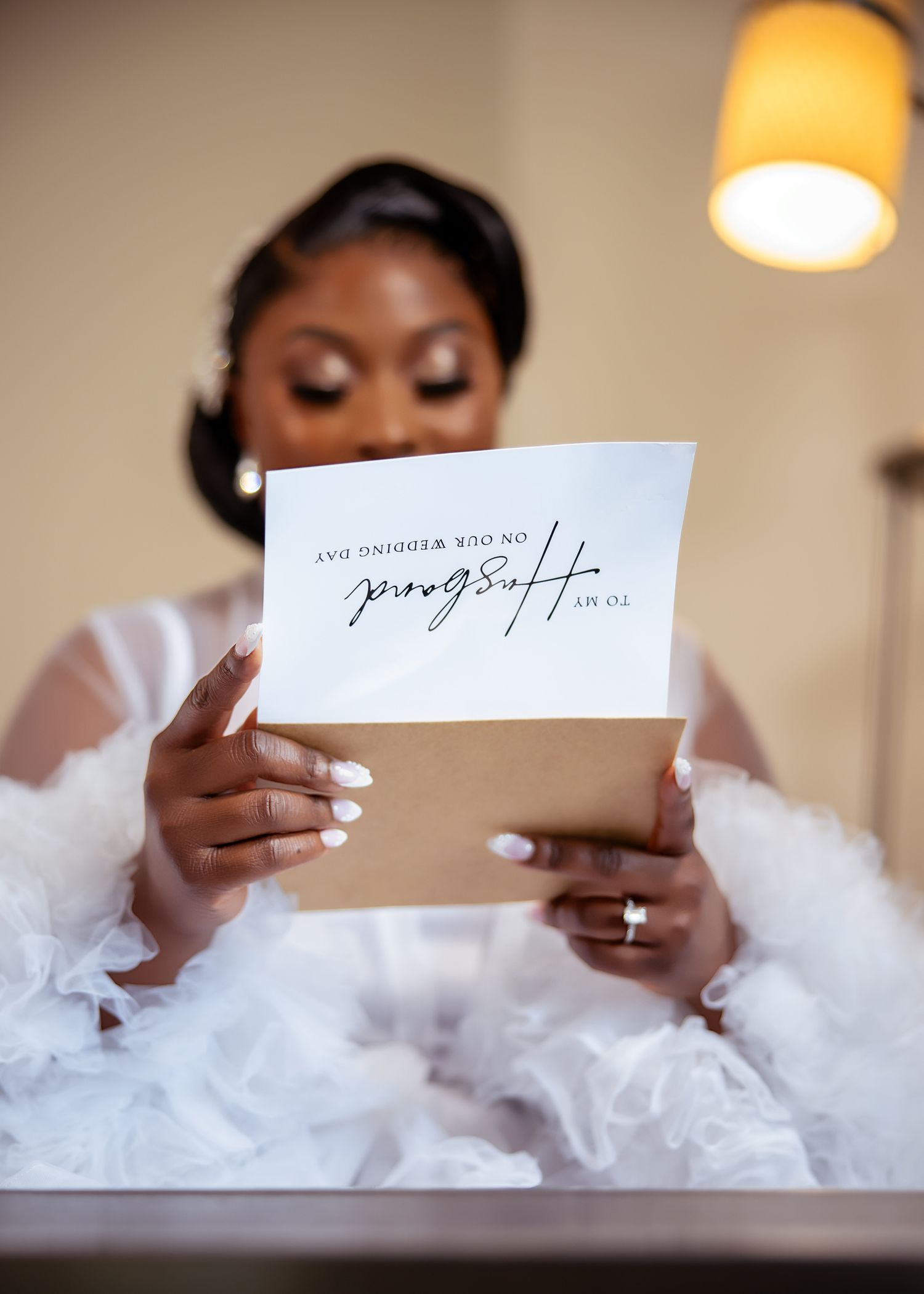 Reading a letter while surrounded by soft white tulle fabric in an indoor setting.