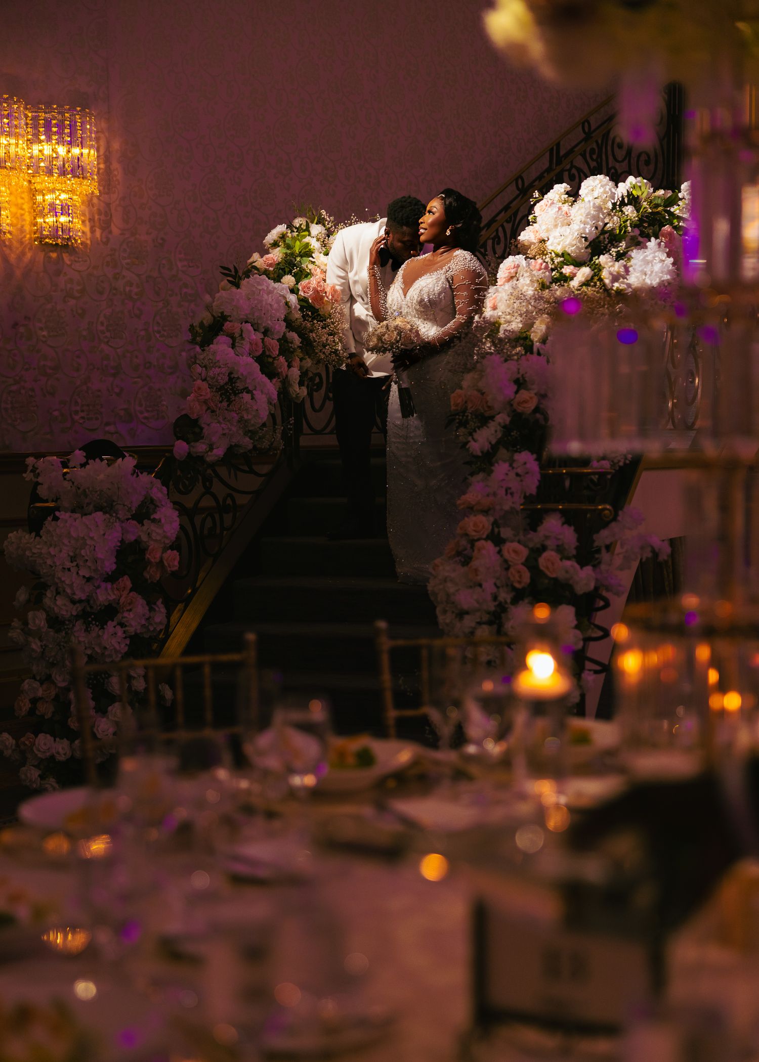 Elegant wedding reception table settings with white floral centerpieces and glowing candlelight create a romantic atmosphere.