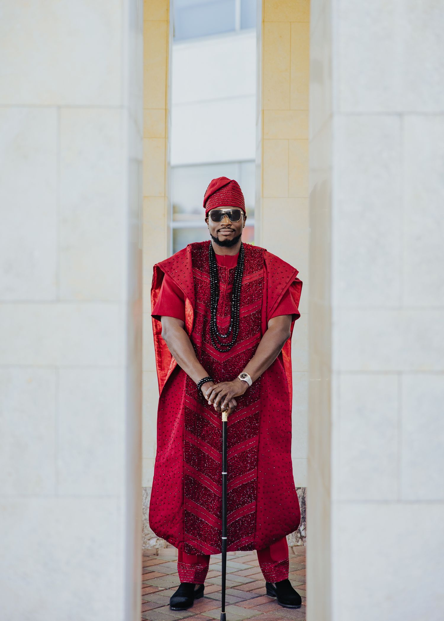 Traditional red and black attire photographed against a light colored architectural backdrop.